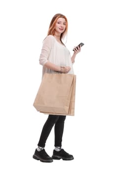 Happy young woman with smartphone and shopping bags. Sale, consumerism, technology and people concept