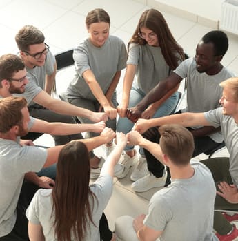 group of young like-minded people making a circle out of their hands. the concept of unity