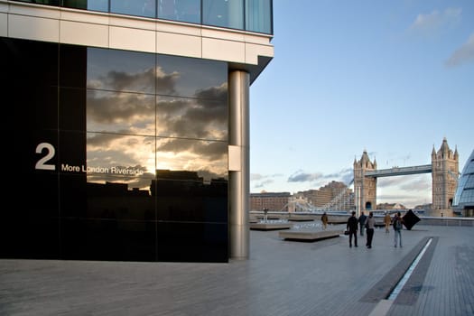 London, United Kingdom - December 17, 2006: Sun shines on "2 More London Estates" wall (design by Foster and Partners). Modern architecture complements traditional style of Tower bridge in background.