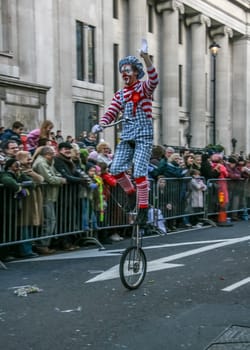 London, United Kingdom - January 1, 2007: Man in clown costume rides unicycle, and waves to cheering crowd, during New Year's Day Parade.