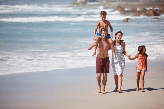 The perfect family getaway. a family walking along the beach
