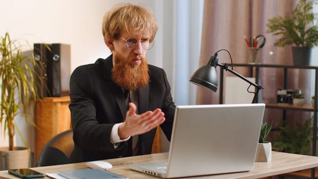 Irritated shocked business man while working on laptop, unexpected online website problem, computer virus data loss by hacking. Manager freelancer feeling mad about broken notebook at office workplace
