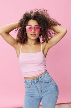 Happy woman afro curls hair dancing on pink background smile with teeth in summer pink t-shirt jeans and glasses, summer vibe, copy space. High quality photo