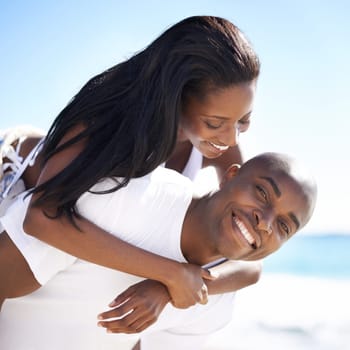 Enjoying the holidays with you is amazing. A handsome african-american man giving his girlfriend a piggyback on the beach