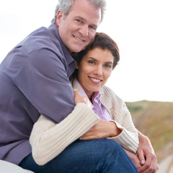 Appreciating one another. A mature couple hugging one another while sitting on a sand dune
