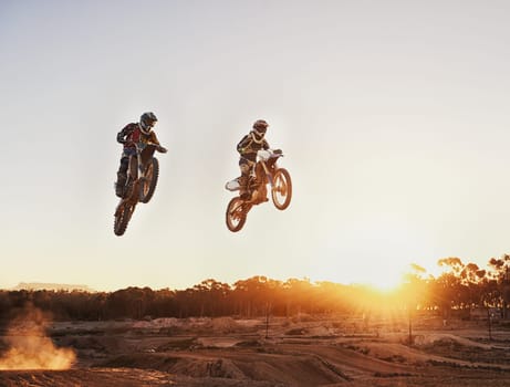 Adventure, speed and motorbike for a competition during a race outdoor for extreme sports. Action, men and motorcycle on racetrack for sport jump on fast transportation in the dirt with sunset