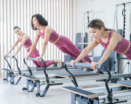 Three asian women doing plank on reformer machine