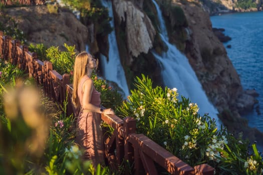 Beautiful woman with long hair on the background of Duden waterfall in Antalya. Famous places of Turkey. Lower Duden Falls drop off a rocky cliff falling from about 40 m into the Mediterranean Sea in amazing water clouds. Tourism and travel destination photo in Antalya, Turkey. Turkiye.