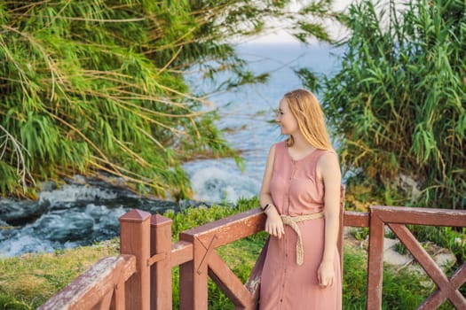 Beautiful woman with long hair on the background of Duden waterfall in Antalya. Famous places of Turkey. Lower Duden Falls drop off a rocky cliff falling from about 40 m into the Mediterranean Sea in amazing water clouds. Tourism and travel destination photo in Antalya, Turkey. Turkiye.