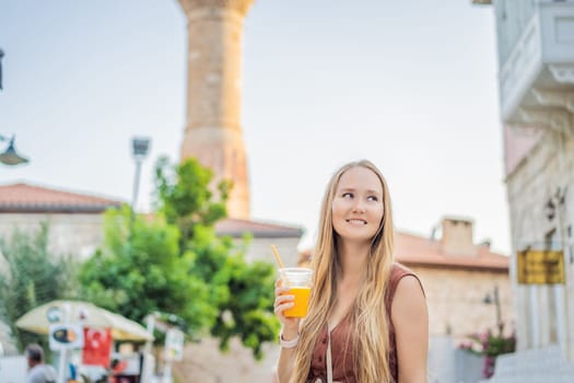 Happy woman tourist with fresh juice on background of old street of Antalya. female tourist traveler discover interesting places and popular attractions and walks in the old city Kalechi of Antalya, Turkey. Turkiye.