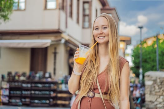 Happy woman tourist with fresh juice on background of old street of Antalya. female tourist traveler discover interesting places and popular attractions and walks in the old city Kalechi of Antalya, Turkey. Turkiye.