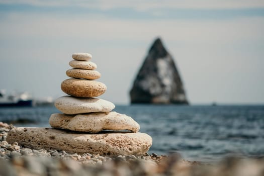 Pyramid stones on the seashore with warm sunset on the sea background. Happy holidays. Pebble beach, calm sea, travel destination. Concept of happy vacation on the sea, meditation, spa, calmness.