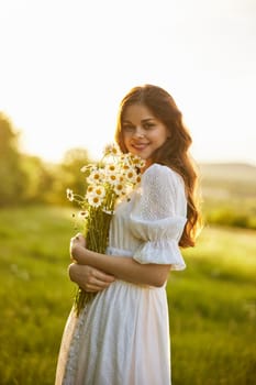 portrait of a woman in a light dress in a field during sunset with a bouquet of daisies in her hands. High quality photo