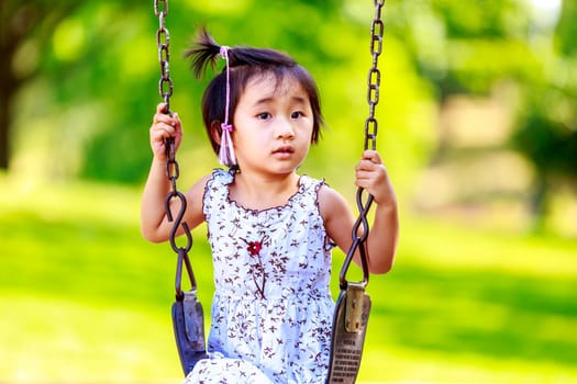 Adorable girl enjoys play time on the swing.