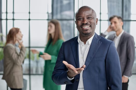 young african businessman raising his open palm against the background of colleagues
