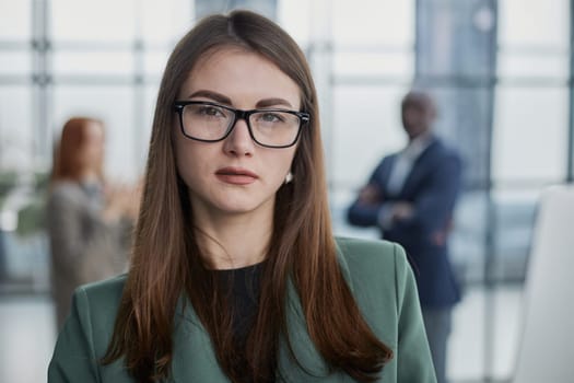 businesswoman or female executive manager in formal suit and eyeglasses, holding laptop and using laptop computer.
