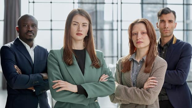 Business people stand with each other in a conference room with their arms crossed