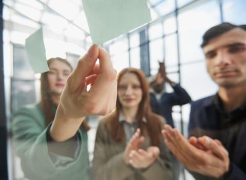 Creative business team looking at sticky notes on glass window