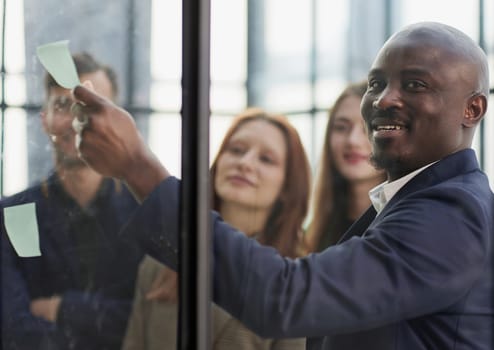 Creative business team looking at sticky notes on glass window