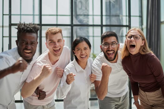 Group of mono-ethnic corporate employees clenching their fists celebrating success