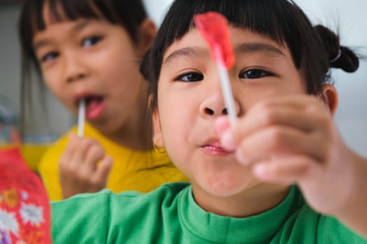 Two happy cute little girls eating lollipops. Funny kid with lollipop candy. Child eating sweets.