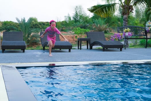 Cute girl with goggles jumping into the pool. Little girl swimming and playing in the water. summer vacation concept.