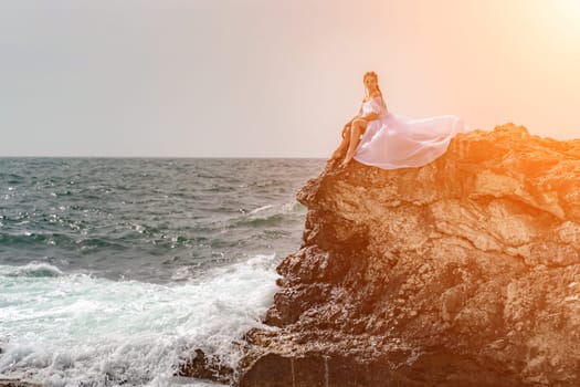 Woman sea white dress. A woman in a storm sits on a stone in the sea. Dressed in a white long dress, waves crash against the rocks and white spray rises