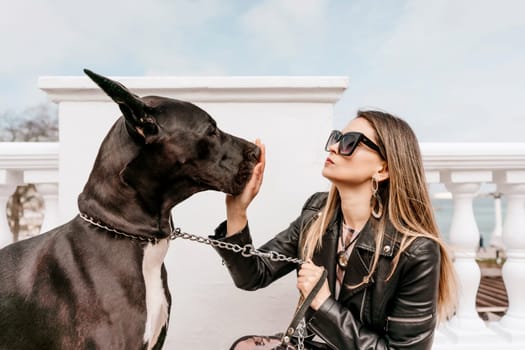 A woman walks with her Great Dane in an urban setting, enjoying the outdoors and the company of her dog