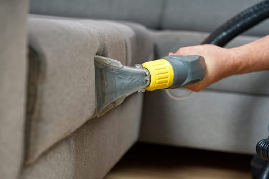 Sofa chemical cleaning with professionally extraction method. Wet textile sofa cleaning. home cleaning service. cleaning sofa with washing suction cleaner closeup.