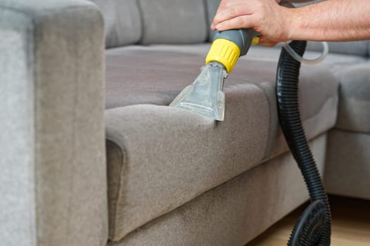 Sofa chemical cleaning with professionally extraction method. Wet textile sofa cleaning. home cleaning service. cleaning sofa with washing suction cleaner closeup.