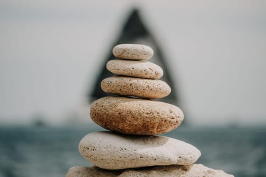 Pyramid stones on the seashore with warm sunset on the sea background. Happy holidays. Pebble beach, calm sea, travel destination. Concept of happy vacation on the sea, meditation, spa, calmness.