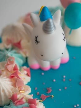 studio shot of chocolate frosted blue dripped icing white cup cake, unicorn , meringue and sprinkles on top