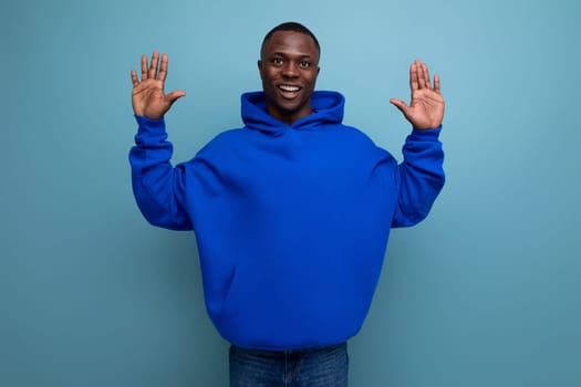 close-up of a laughing black american man in a sweatshirt with a hood on a studio background with copy space.