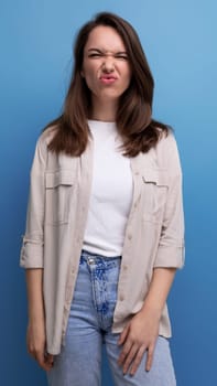 optimistic brunette young brunette lady dressed in shirt and jeans with grimace.