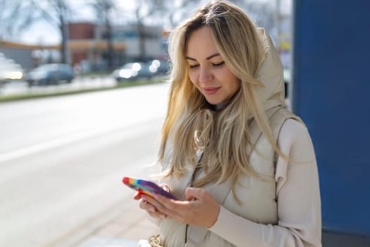 Cheerful female tourist using mobile phone for view map via network and continue her walk in strange city, beautiful hipster girl in good mood consult bus schedule via internet on her cell telephone .