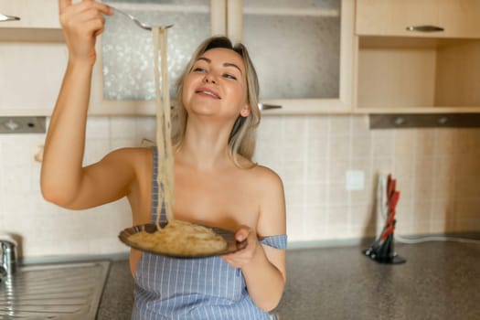 Sexy blonde housewife eating cooked pasta portrait close-up.