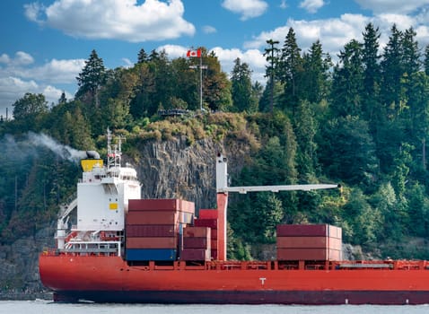 Container freight vessel is passing by Stanley Park in Vancouver harbor.