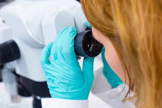 Scientist looking through a microscope doing research in a laboratory.