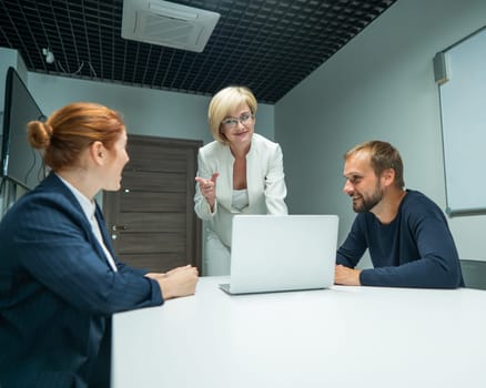 Blond, red-haired woman and bearded man in suits in the office. Business people are negotiating in the conference room