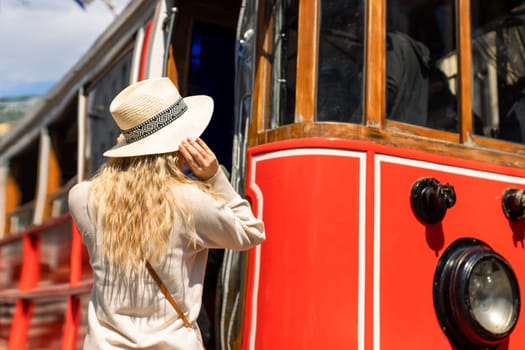 Beautiful young girl tourist in a hat poses in front of tram at popular Istiklal street in Beyoglu, Istanbul, Turkey .