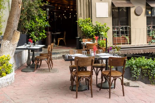 Elegant wooden table and empty chairs near the cafe against the background of the window and the wall of the old city.