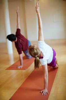 Doing some side planks. two people doing yoga together in a studio