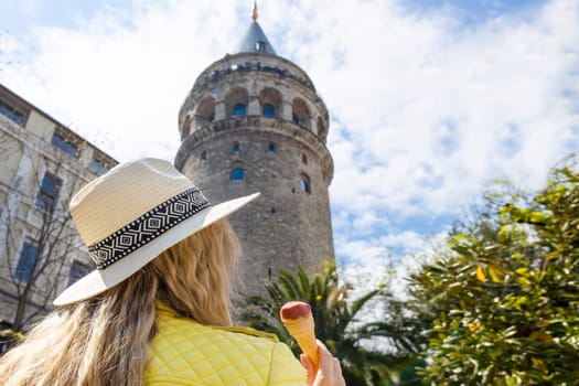 Beautiful young tourist girl in fashionable clothes poses with view of landmark Galata tower in Beyoglu,Istanbul,Turkey.Traveler Concept image.