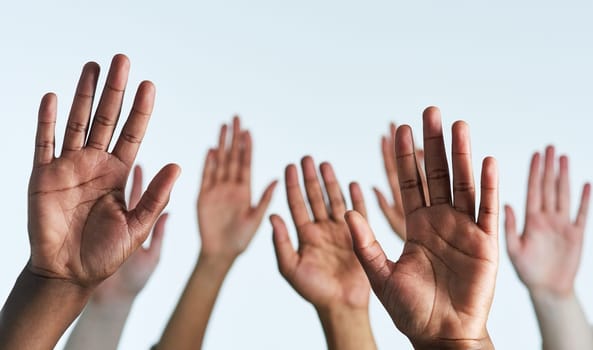Shot of a group of hands reaching up against a white background.