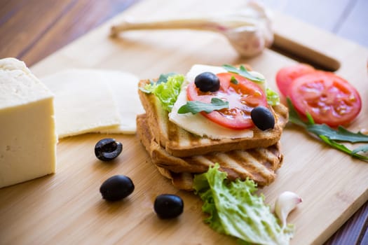 fried toasts with mozzarella, lettuce and tomatoes with herbs on a wooden table