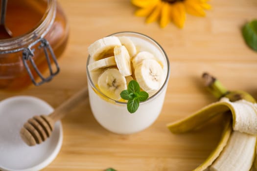 Sweet homemade yogurt with bananas and honey in a glass