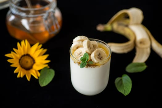 Sweet homemade yogurt with bananas and honey in a glass