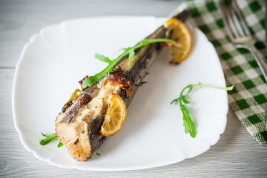 Baked fish with seasonings and spices in a plate on a wooden table