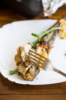 Baked fish with seasonings and spices in a plate on a wooden table