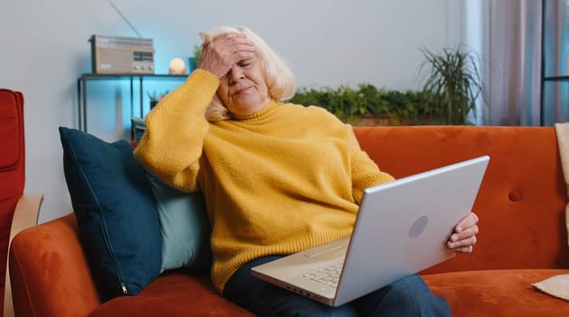 Tired senior woman use laptop, suffering from headache problem tension and migraine, stress at home. Elderly grandmother works on notebook, sends messages, makes online purchases, watching movies